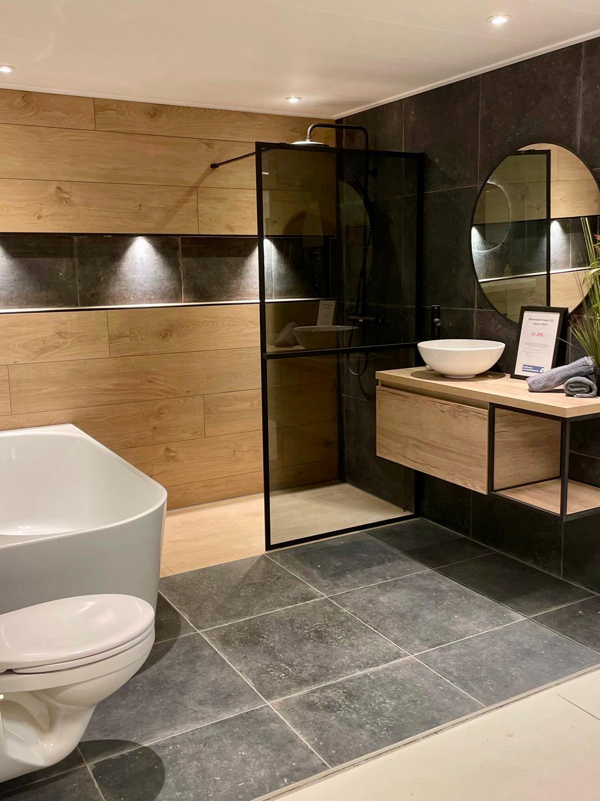 Luxe moderne badkamer renovatie met houtlook wandpanelen, zwarte tegels, inloopdouche en vrijstaand bad door BadkamerInstalleren.nl